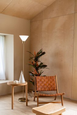 Ahşap ve cam vazodaki yapay bitkilerle kaplı rattan deri koltuklu şık bir yaşam köşesi arka planda kontrplak duvarlı / rahat iç tasarım / modern iç tasarım