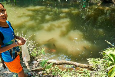 Luang Prabang. Laos. 04.20.2019. Kuang Si Şelalesi'nde çocuk balık besliyor