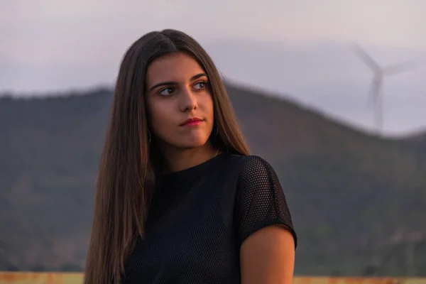 Hermosa joven morena posando una carretera en medio del campo al atardecer — Foto de Stock