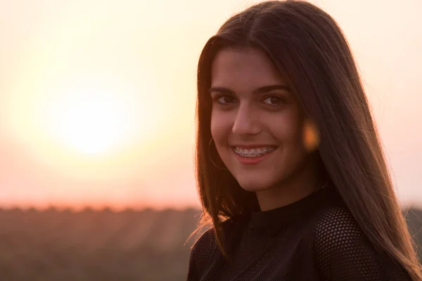 Hermosa joven morena posando una carretera en medio del campo al atardecer — Foto de Stock