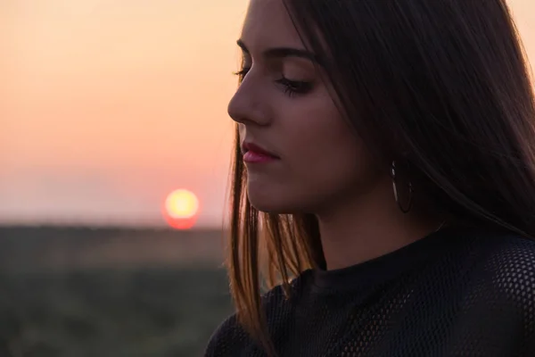 Красива молода брюнетка дівчина позує дорогу посеред поля на заході сонця — стокове фото
