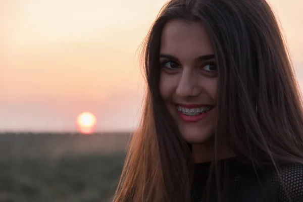 Hermosa joven morena posando una carretera en medio del campo al atardecer — Foto de Stock