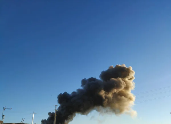 Огромный шлейф черного дыма от огня, поднимающегося высоко над плоской землей против голубого неба. Севилл, Испания — стоковое фото