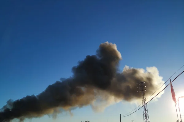 Дым против неба. Огромный чёрный дымовой шлейф от промышленного огня — стоковое фото