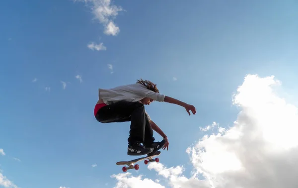 Madrid, Spanje; 1 maart 2019: een tiener skateboarder springen op achtergrond van blauwe hemel met wolken — Stockfoto