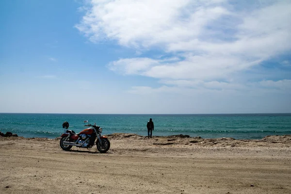 Almerimar, Espanha; 20 de fevereiro de 2019: motociclista olhando para o mar ao lado de sua moto na praia — Fotografia de Stock