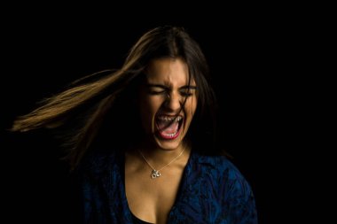 Genç esmer kız, uzun düz saçlı, bağıran kızgın, siyah arkaplan