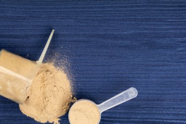 Kepçeler arka plan mavi ahşap üzerinde protein tozları ile dolu