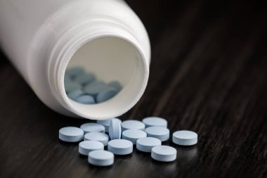 İlaç şişesi ve mavi haplar ahşap arka plana döküldü. Farmasötik ilaçlar.
