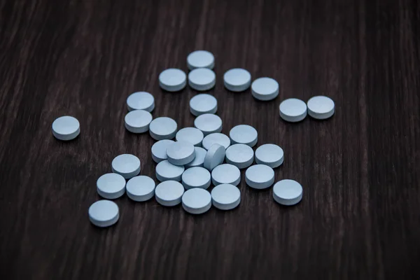 Generic blue erectile dysfunction pills on wood background.