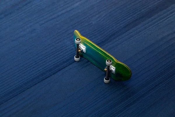 Fingerboard. A small skateboard for kids and teenagers to play with hand fingers. Isolated on blue wood background