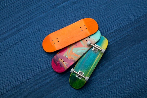 Fingerboard. A small skateboard for kids and teenagers to play with hand fingers. On blue wood background