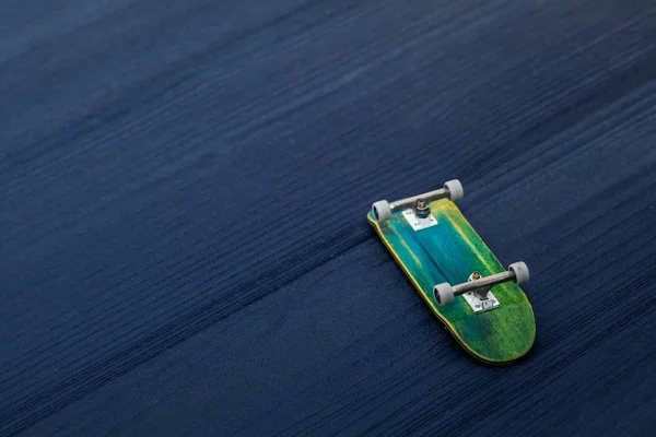 Giocattolo di tastiera in miniatura in legno skateboard su sfondo di legno blu — Foto Stock