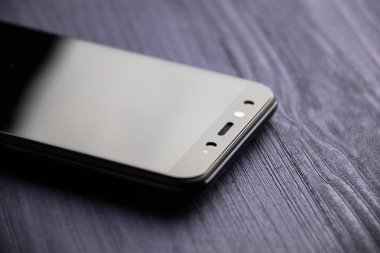 Kameralı siyah modern bir akıllı telefon. Mavi ahşap masaya yakın