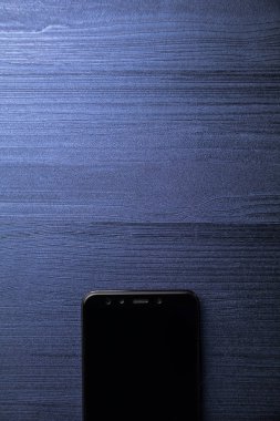 Kameralı siyah modern bir akıllı telefon. Mavi ahşap masaya yakın. kopyalama alanı