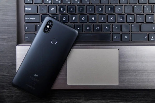 Granada, Spain, January 10, 2019: Modern notebook and smartphone, Mobile with dual camera and fingerprint reader. Xiaomi Mi A2 — Stock Photo, Image