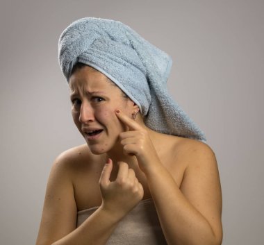 Kız bir havlu ile banyo ve korkmuş sonra, yüzünde sivilce işaret