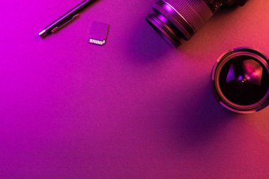 Kamera, kalem, balık gözü lens ve Sd kart. Pembe ışık. Çalışma alanı üst görünümü. Kopyalama alanı
