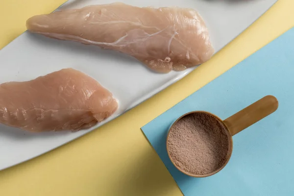 Raw chicken Breasts and a whey protein scoop cocoa flavor. Sport nutrition — Stock Photo, Image