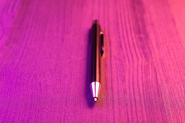 Caneta elegante sobre fundo de madeira e luz rosa. Business caneta preta . — Fotografia de Stock