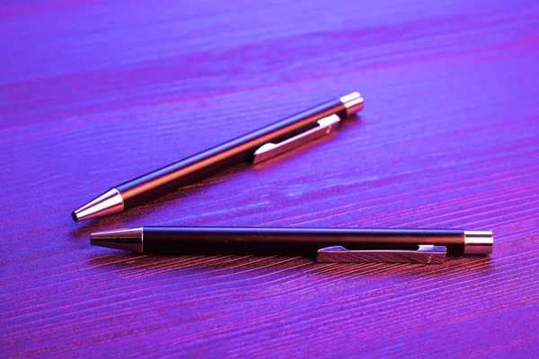 Дві елегантні ручки на фоні дерева і блакитне світло. Бізнес чорна ручка . — стокове фото
