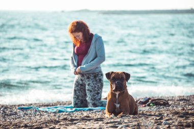 kız yoga yapıyor ve köpeği ile sahilde uzanan