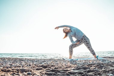 kız yoga yapıyor ve köpeği ile sahilde uzanan