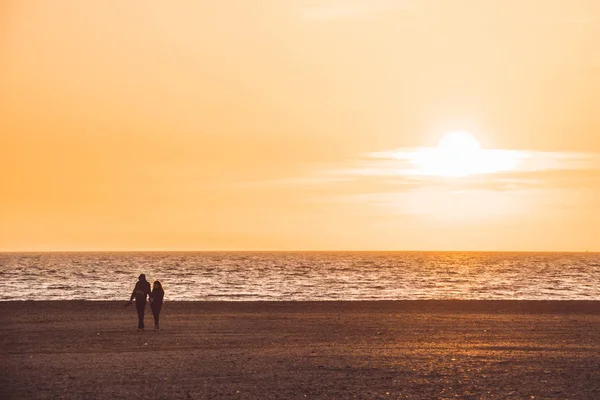 Silhouette de couple marchant sur la plage sur fond de coucher de soleil orange, almerimar, almeria, espagne — Photo