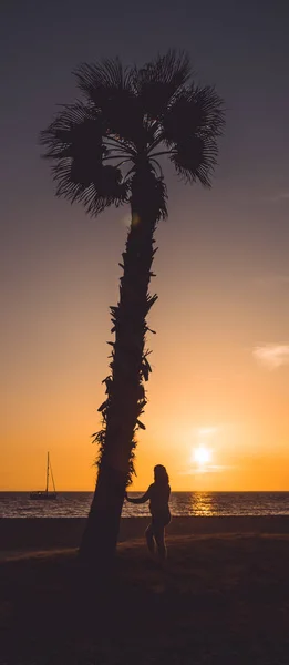 Zwangere vrouw die haar buik aanraakt en zonsondergang kijkt, naast een palmboom, in Almerimar, Almeria, Spanje — Stockfoto