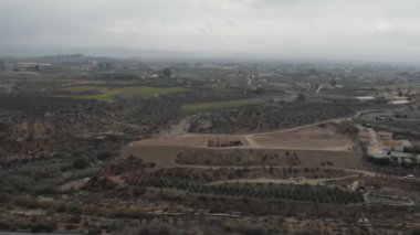 Kolza tarlalarındaki domuz çiftliğinin yakınındaki biyogaz bitkisi üzerinde kamera lı uçuş. Biyokütleden yenilenebilir enerji. Avrupa Birliği'nde modern tarım ve çevre. Endüstriyel manzaraya havadan görünüm.