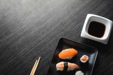 Ahşap masada zarif suşi. Bazı Nigiri, soya sosu ve çubuk ile