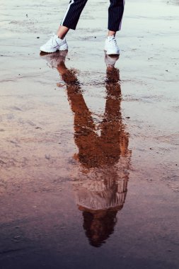 reflected silhouette of a girl in a puddle on sunset clipart