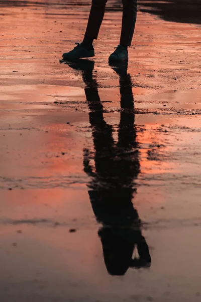 Silhueta refletida de uma menina em uma poça no pôr do sol — Fotografia de Stock