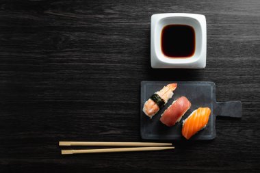 Ahşap masada zarif suşi. Bazı Nigiri, soya sosu ve çubuk ile