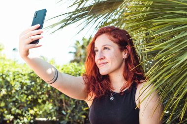 Beyaz kadın parkta akıllı telefon ile selfie çekiyor
