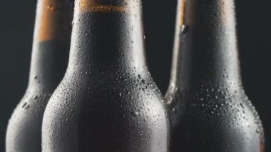 Üç çok soğuk bira şişeleri siyah arka plan üzerinde dönen. Yakın çekim