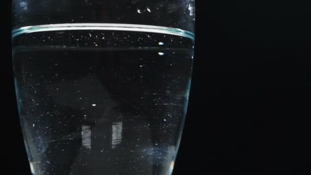 Vaso Agua Girando Sobre Fondo Negro — Vídeo de stock