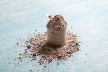 Mavi arka plan üzerinde ölçüm plastik kaşık protein tozu