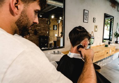 Erkekler Kuaför Salonu. Berberde berberlik yapan berber. Genç Erkek Müşteri ve Kuaför.