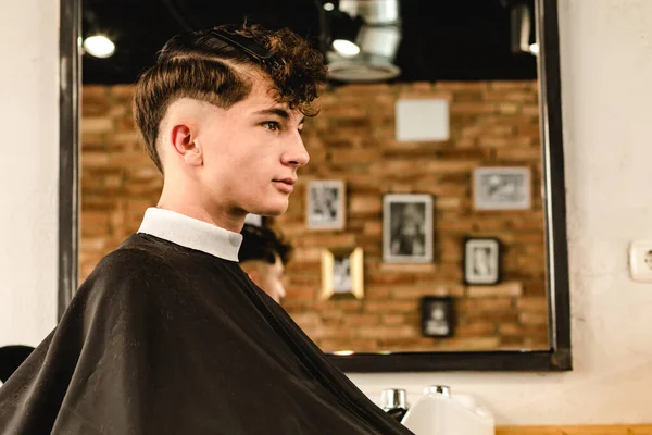 Adolescente recebendo um corte de cabelo moderno em uma barbearia vintage — Fotografia de Stock