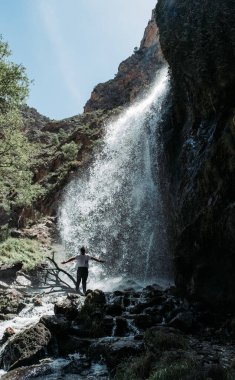 Genç adam büyük bir şelalenin altında