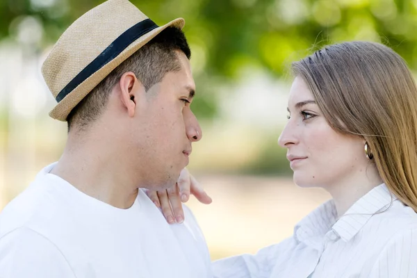 Jovem casal olhando uns para os outros olhos em um parque. Homem latino e mulher caucasiana — Fotografia de Stock