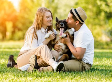 Köpeğiyle parkta eğlenen sevimli bir çift.