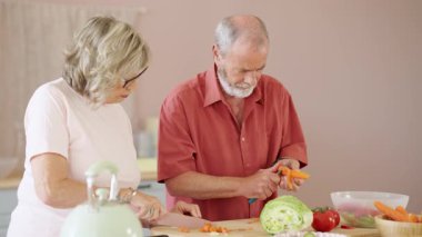 Mutfakta sebze doğrayıp biçen yaşlı bir çift sağlıklı bir yaşam tarzının tadını çıkarıyor.