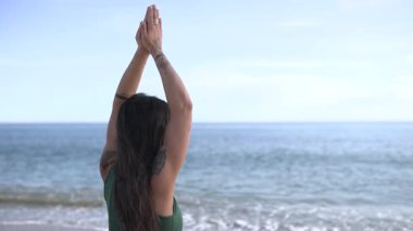 Profesyonel yoga eğitmeni kumlu sahilde meditasyon yoga yapıyor. Altın güneş ışığı saatleri boyunca engin okyanus ufkuyla yüzleşiyor.