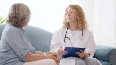 Kadın tıbbi uzman, özel sağlık hizmetleri danışmanlığı sırasında sağlık sorunlarını belgelerken kıdemli hastayı dikkatle dinliyor.