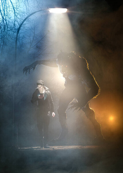 Werewolf attacks from behind a man looking at the phone in a scary e foggy night under lamplight and moonlight  - concept art - 3D rendering 