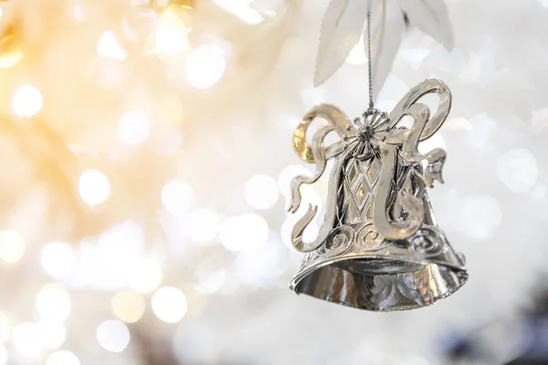 silver christmas bell decoration on blurred sparkling holiday background