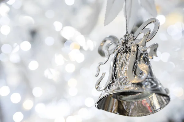 silver christmas bell decoration on blurred sparkling holiday background