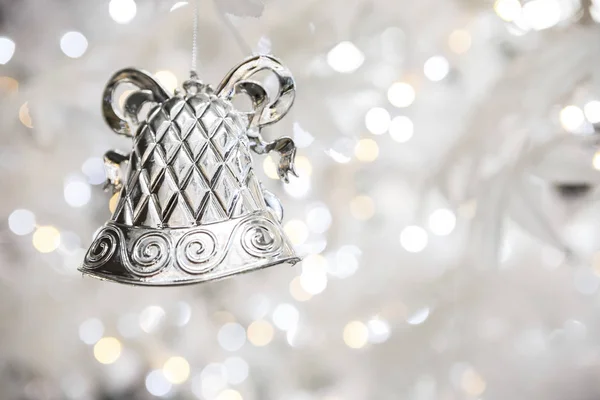 silver christmas bell decoration on blurred sparkling holiday background